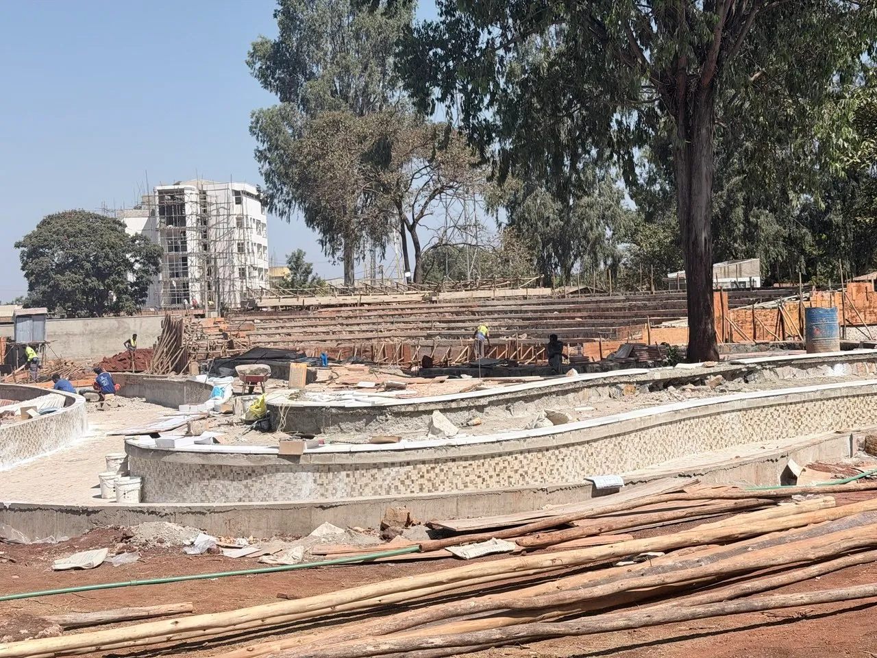 Workers finishing the curved pond wall with stone mosaic at Assosa City Park